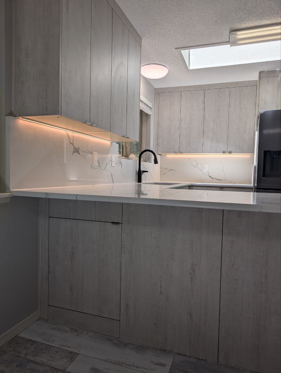 Gray kitchen with undercabinet lighting and gray flooring