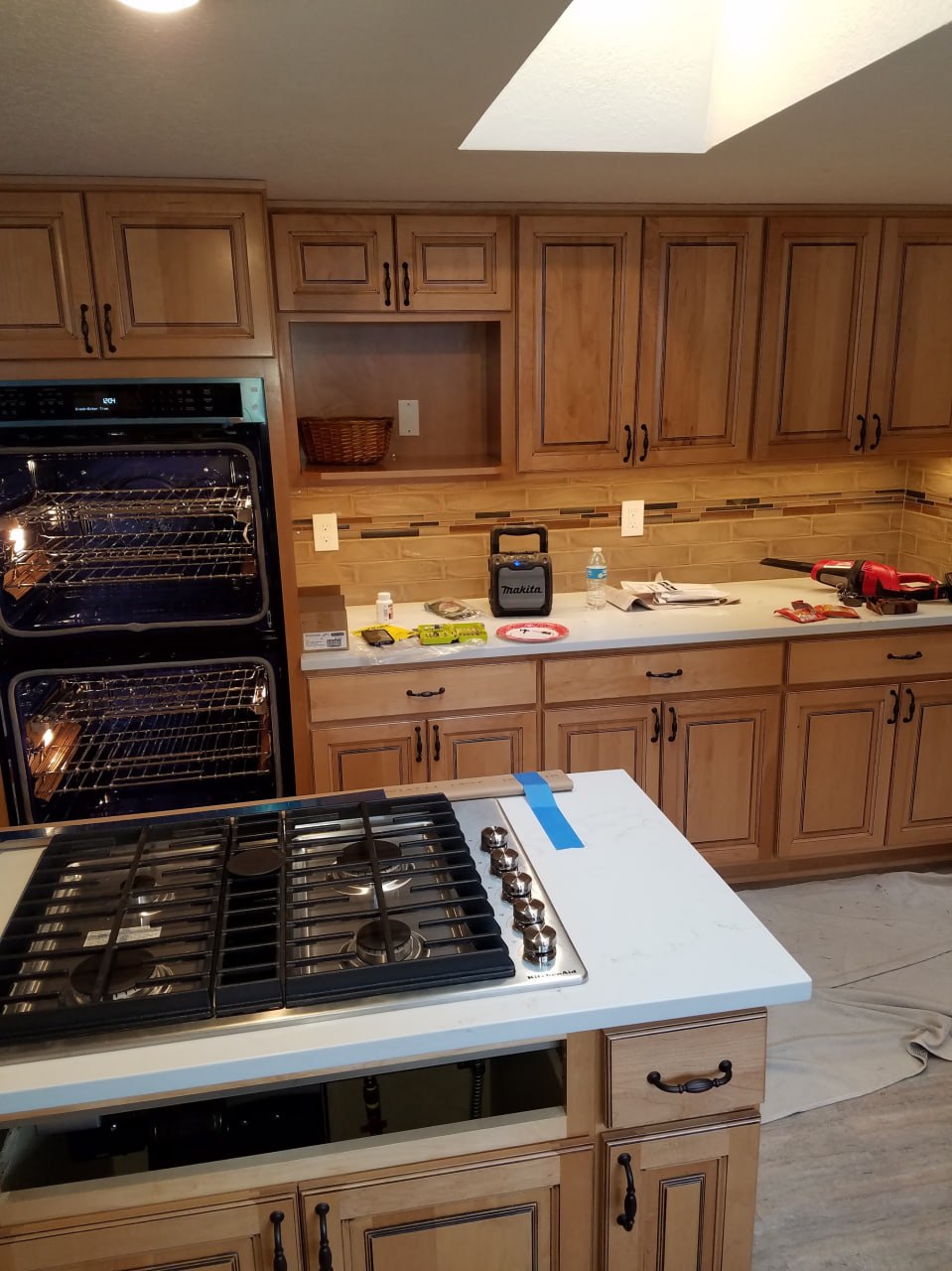 Wood-cabinet kitchen with double ovens and cooktop during electrical work